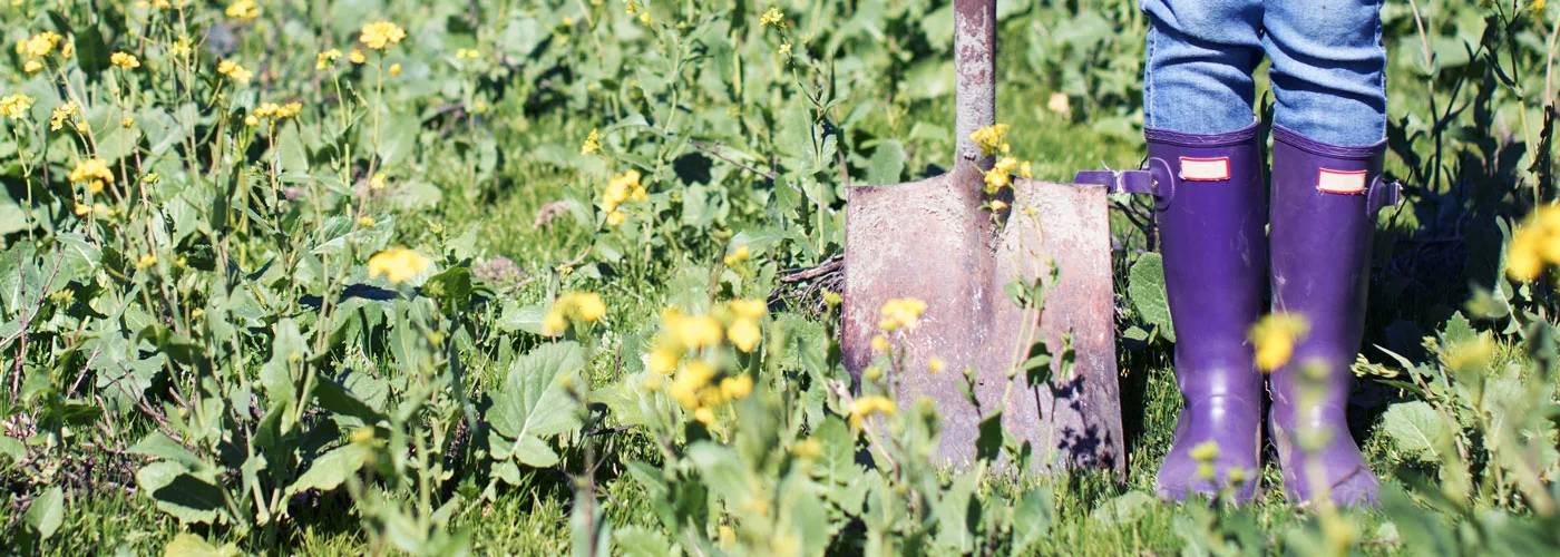 Close up of boots and a shovel in a garden